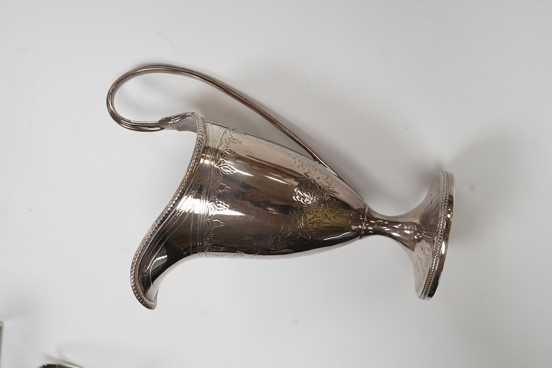 A George III engraved silver helmet shaped cream jug, Henry Chawner, London 1788(repair), height 15.3cm, together with two George V silver toast racks, a silver mounted glass toilet jar and a modern silver mounted bottle